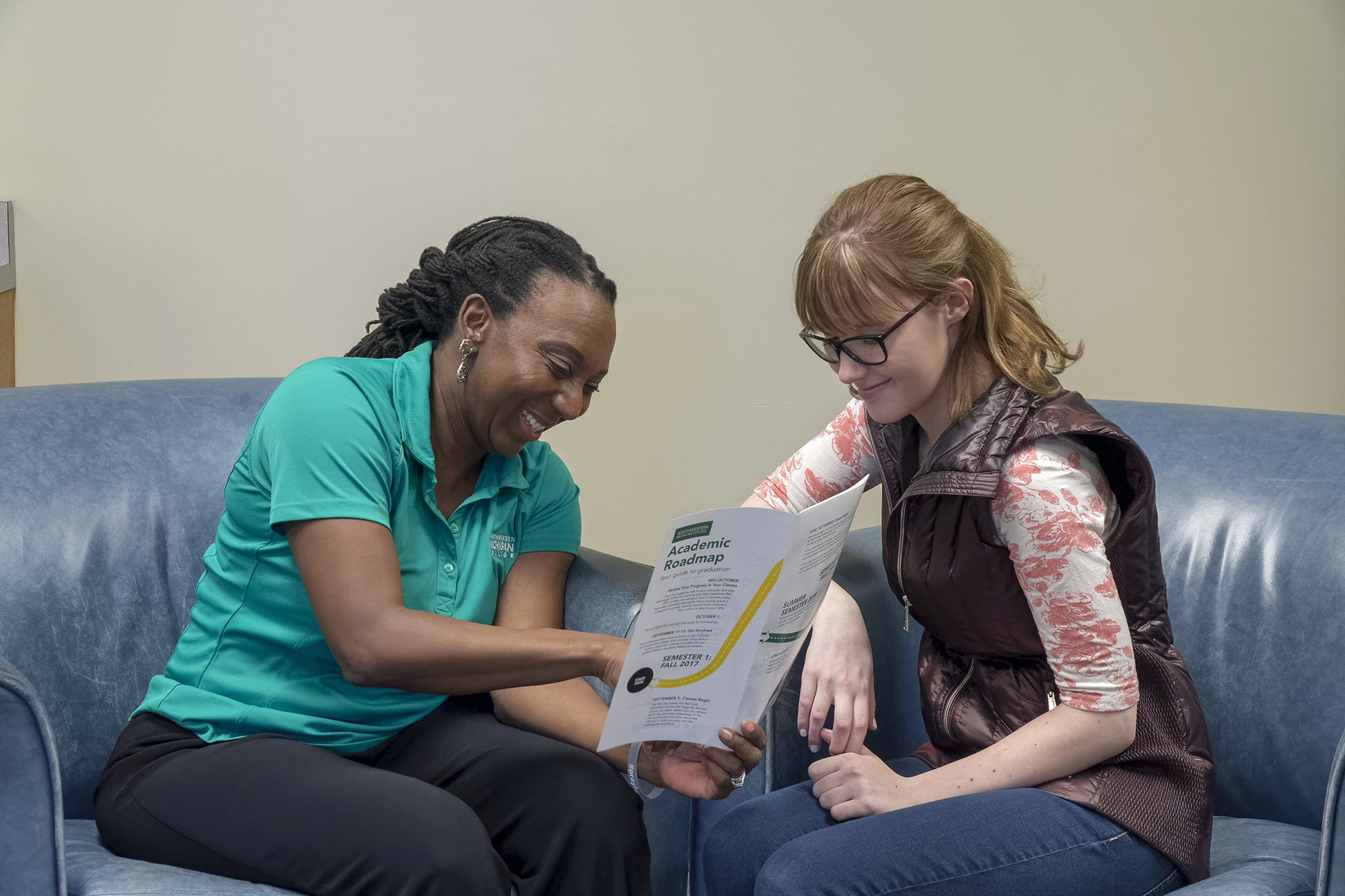 Advisor sitting with a student and showing them a brochure about a program