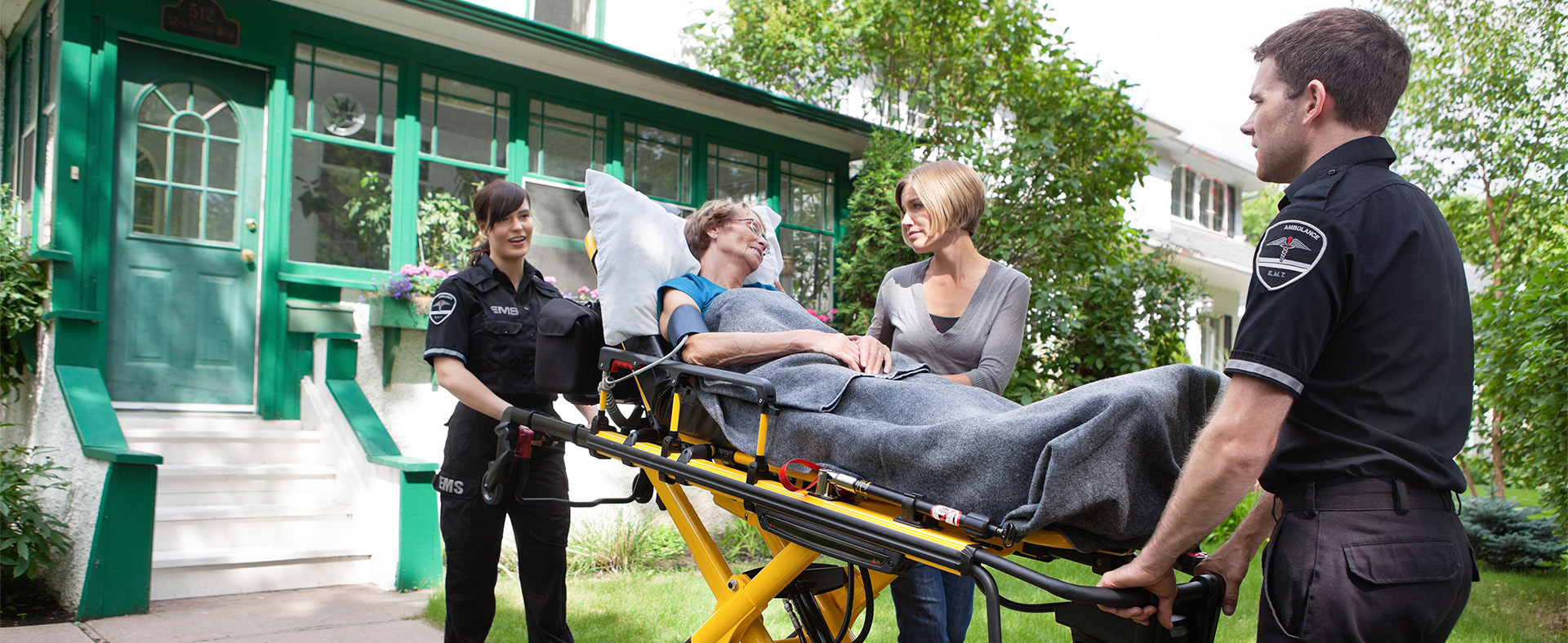 Senior Woman on Ambulance Stretcher Being Helped by EMT